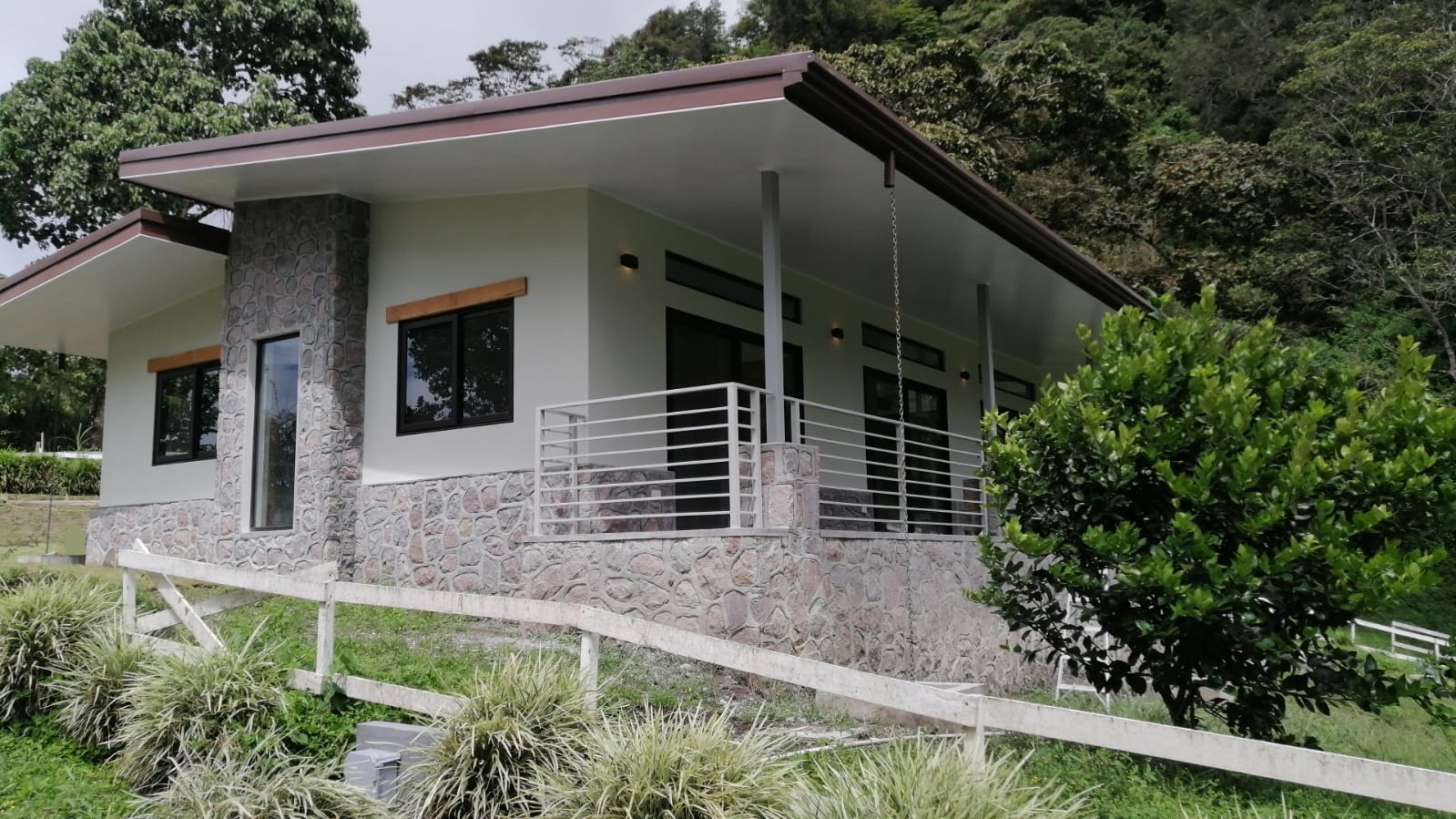 Modern hillside residence with stone facade surrounded by tropical forest